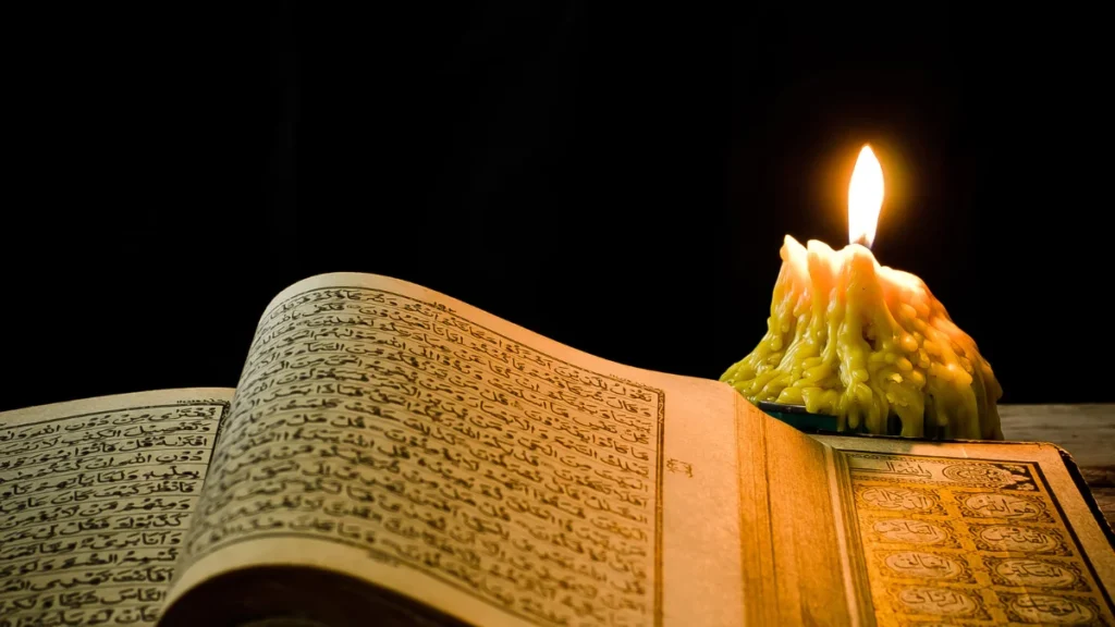 Open Holy Quran next to a lit candle